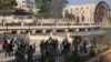 Syrian anti-government fighters gather among civilians near of one of Hama's water wheels, or norias, after forces captured the city on Dec. 6, 2024.