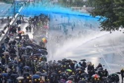FILE - Pro-democracy protesters react as police fire water cannons outside the government headquarters in Hong Kong.