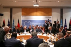 FILE - Members of the international committee take their seats for a follow-up meeting on Libya, arranged by German Foreign Minister Heiko Maas, in Munich, Germany, Feb. 16, 2020.