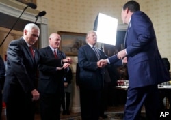FILE - Vice President Mike Pence, left, and Secret Service Director Joseph Clancy stand as President Donald Trump shakes hands with FBI Director James Comey during a reception for inaugural law enforcement officers and first responders in the Blue Room of the White House.