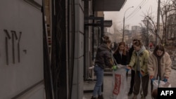 Місцева молодь прибирає розбите скло на місці ракетного обстрілу в Києві 20 грудня 2024 року. Roman PILIPEY/AFP