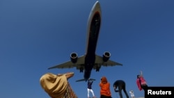 FILE - Tourists take pictures at Mai Khao Beach, as a plane approaches the Phuket International Airport in Phuket, Thailand March 17, 2016. 