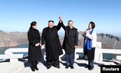 South Korean President Moon Jae-in and North Korean leader Kim Jong Un pose for photographs on the top of Mt. Paektu, North Korea, Sept. 20, 2018.