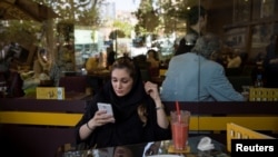 FILE - An Iranian woman uses her mobile phone in a coffee shop in Tehran, May 17, 2017.