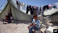 A Syrian refugee boy sits outside his family's tent at a temporary camp in the Lebanese town of Marj near the border with Syria, May 20, 2013. 