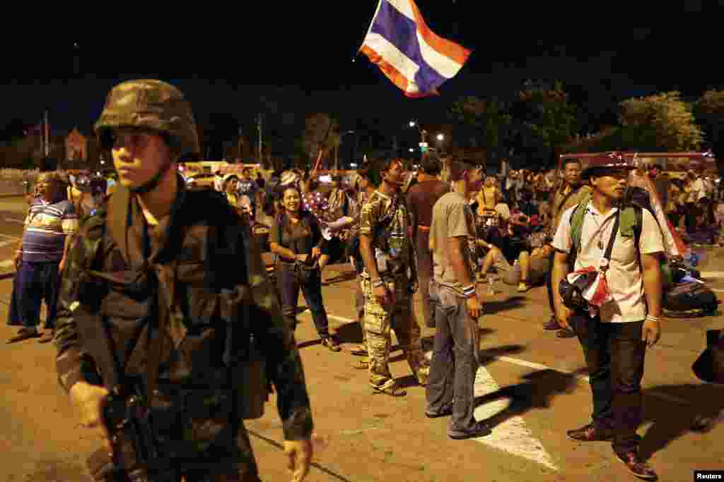 Anti-government protesters waiting at the Royal Plaza for transportation home stand behind a soldier after the coup was declared in Bangkok, May 22, 2014. 