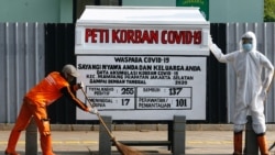 Seorang petugas kebersihan sedang bekerja di depan patung dan hiasan seperti peti jenazah untuk meningkatkan kesadaran masyarakat tentang virus corona (COVID-19), di Jakarta, 19 Agustus 2020. (Foto: Reuters)