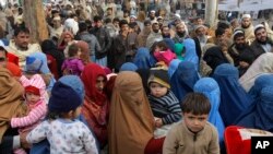 FILE - Afghan refugee families wait for their turn to be registered outside the government registration office in Peshawar, Pakistan, Feb. 8, 2017.