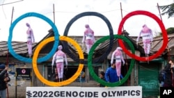 FILE - Exile Tibetans use the Olympic rings as a prop as they protest the holding of the 2022 Winter Olympics in Beijing, in Dharmsala, India, Feb. 3, 2021. 