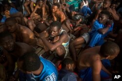 Migrants sit on the deck of the vessel of Proactiva Open Arms after being rescued in the Mediterranean Sea, about 15 miles north of Sabratha, Libya on July 25, 2017.