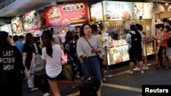 FILE - Tourists walk near food stalls at Ximending shopping district in Taipei, Taiwan Aug. 3, 2017.