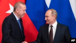 FILE - Russian President Vladimir Putin, right, and Turkish President Recep Tayyip Erdogan shake hands during a news conference after their talks in the Kremlin, in Moscow, March 5, 2020.