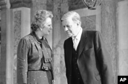 FILE - Britain's Prime Minister Margaret Thatcher, left, speaks to West German Chancellor Helmut Schmidt as they walk in the gardens of the palace of Versailles near Paris, France.