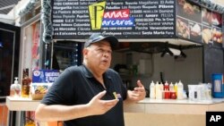 Venezuelan national Fernando Fernandez gestures as he is interviewed in front of his fast food stand in Bogota, Colombia, Dec. 22, 2017. Fernandez said he left Venezuela two years ago because of the country's economic crisis.