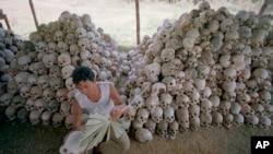 FILE - A man cleans a skull near a mass grave at the Chaung Ek torture camp run by the Khmer Rouge in this undated photo. 