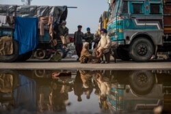Indian farmer Surender Singh, 70, sits on a chair and gets a massage, next to a truck parked on a highway as part of protests against new farm bills, at the Delhi-Haryana state border, India, Dec. 1, 2020.