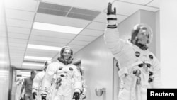 FILE - Apollo 11 astronaut Neil Armstrong waves to well-wishers on the way out to the transfer van, Cape Canaveral, Florida, July 16, 1969. Mike Collins and Buzz Aldrin follow Armstrong down the hallway.