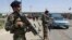 In this July 10, 2018 photo, an Afghan national army soldier stops a car at a temporary checkpoint on the outskirts of Kabul, Afghanistan.