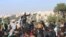 FILE - In this frame grab from video taken on Dec. 20, 2019, Hayat Tahrir al-Sham militants try to disperse people gathered at the Bab al-Hawa border gate to protest the ongoing bombing campaign in Syria's rebel-controlled Idlib province.