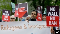 Protesters hold signs during a demonstration against President Donald Trump's revised travel ban, May 15, 2017, outside a federal courthouse in Seattle.