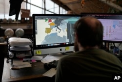 An artist uses computer to create a map at a studio in London, Tuesday, Feb. 27, 2024. Globes in the age of Google Earth capture the imagination and serve as snapshots of how the owners see the world and their place in it. (AP Photo/Kin Cheung)