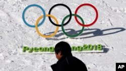 FILE - A man walks by the Olympic rings with a sign of 2018 Pyeongchang Olympic Winter Games, in Pyeongchang, South Korea, Feb. 3, 2017. 