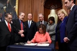 FILE - House Speaker Nancy Pelosi of Calif., signs the resolution to transmit the two articles of impeachment against President Donald Trump to the Senate for trial on Capitol Hill in Washington, Wednesday, Jan. 15, 2020.