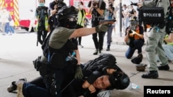 A police officer raises his pepper spray handgun as he detains a man during a march against the national security law at the anniversary of Hong Kong's handover to China from Britain in Hong Kong, July 1, 2020.