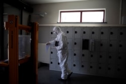 A worker in protective gear carries an urn of ashes of a COVID-19 victim at the Pontes crematorium and funeral center in Wilrijk, Belgium, April 3, 2020. An extra 200 COVID-related cremations had been done since the start of the week.
