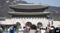 Visitors walk near the Gwanghwamun, the main gate of the 14th-century Gyeongbok Palace, one of South Korea's well known landmarks, in Seoul, South Korea, Thursday, Feb. 27, 2025. (AP Photo/Lee Jin-man)