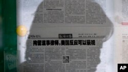 资料照片:一名女子在北京的某处报纸橱窗阅读《环球时报》。该报的文章呼吁忽视美国对中国打压维权律师的批评。(2015年7月14日)