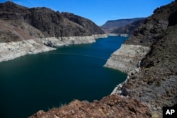 FILE - In this May 31, 2018 photo, the low level of the water line is shown on the banks of the Colorado River in Hoover Dam, Ariz.