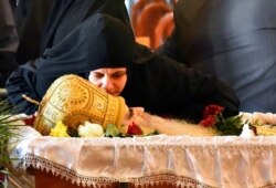 FILE - A nun kisses Bishop Amfilohije during the liturgy and funeral in the main temple in Podgorica, Montenegro, Nov. 1, 2020. The bishop, head of the Serbian Orthodox Church in Montenegro, died after contracting COVID-19.