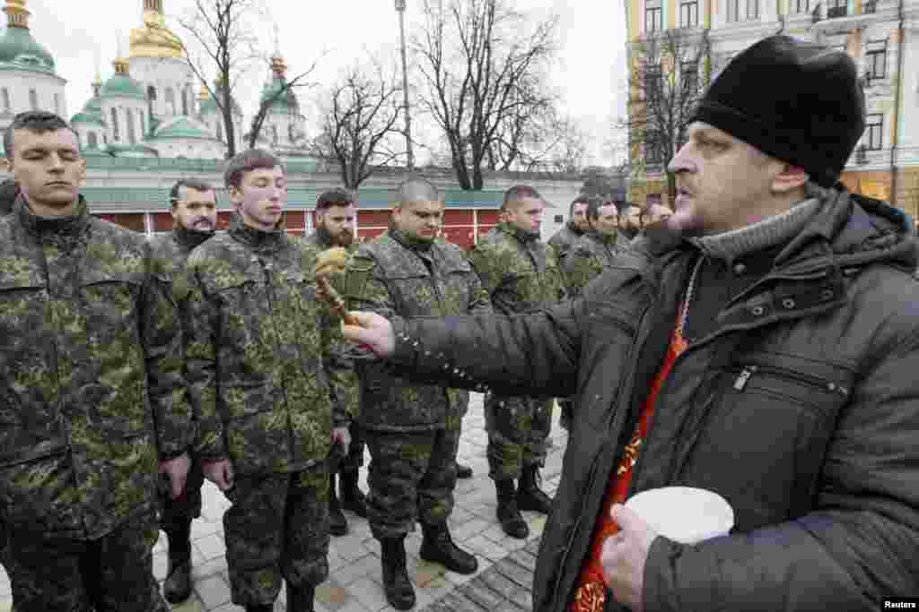 An Orthodox priest blesses members of the newly-created Ukrainian Interior Ministry battalion "Saint Maria" during a ceremony before they head to militay training, in front of St. Sophia Cathedral, in Kyiv, Feb. 3, 2015.