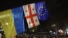 Демонстранти йдуть біля прапорів України, Грузії та Європи під час акції протесту проти рішення уряду відкласти переговори про вступ до ЄС до 2028 року, Тбілісі, 30 листопада 2024 року. Giorgi ARJEVANIDZE/AFP