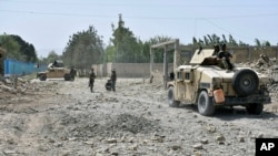 FILE - Afghan Security personnel inspect the site of truck suicide bombing in the northern Balkh province of Afghanistan, Aug. 25, 2020. 