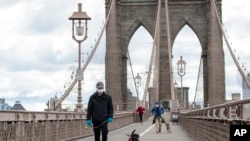 Ljudi sa maskama šetaju po Bruklinskom mostu u Njujorku. 