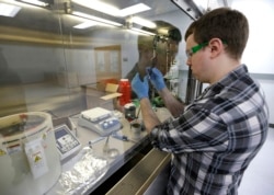 Caleb Ogier, a PhD student in mechanical engineering at the University of Washington, works in a fume hood with ink used to produce electrical circuits, at the newly opened Washington Clean Energy Testbeds laboratory housed in the University of Washington