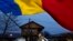 A man waves the Romanian flag outside a voting station after Romania's Constitutional Court annulled the first round of presidential elections, in Mogosoaia, Romania, Dec. 8, 2024. 