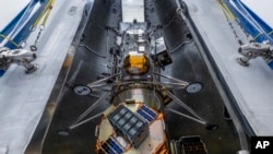 In this undated image released by NASA, Intuitive Machines’ newest lunar lander is seen attached to a SpaceX Falcon rocket.