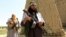 FILE - Members of the Taliban walk in Ghanikhel district of Nangarhar province, Afghanistan, June 16, 2018.