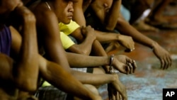 FILE - Rounded up residents, mostly males, wait to be transported to a police station in the continuing operation of President Rodrigo Duterte's so-called "War on Drugs" campaign, at the slum community of Tondo, in Manila, Philippines, Sept. 30, 2016.
