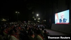 People watch as Prime Minister Narendra Modi delivers an address to the nation, on a TV screen in Ahmedabad, India, Aug. 8, 2019. 