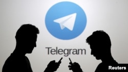 ARSIP - Dua pria berpose dengan telepon pintar di depan layar yang memperagakan logo aplikasi Telegram (foto: REUTERS/Dado Ruvic)