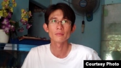 FILE - Before his arrest, Vietnamese blogger Dinh Nhat Uy holds a sign protesting China's territorial claims in the South China Sea.