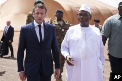 French President Emmanuel Macron, left, talks to Mali's President Ibrahim Boubacar Keita as they meet French soldiers of Operation Barkhane, France's largest overseas military operation, in Northern Mali, May 19, 2017.