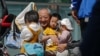 An elderly man plays with children near a commercial office building in Beijing on May 10, 2021. 