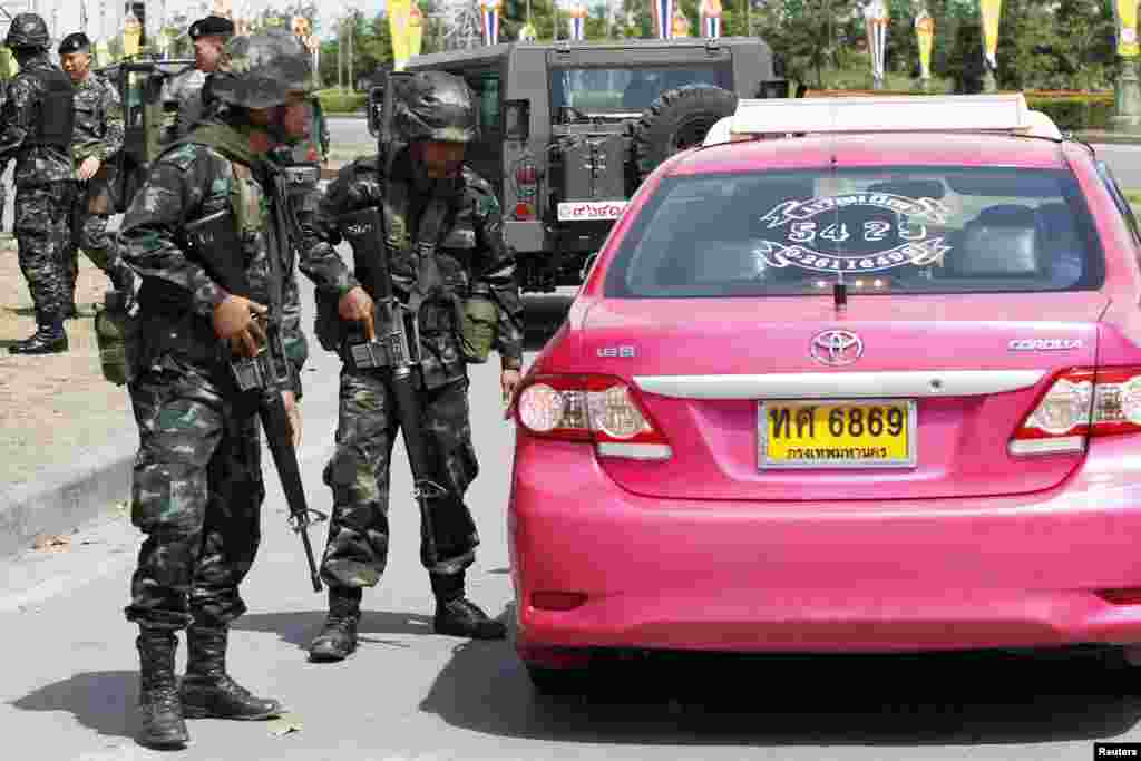 Thai soldiers check a taxi near the site where pro-government "red shirt" supporters gather, in the suburbs of Bangkok, May 20, 2014.