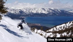 With Lake Tahoe as a backdrop, a skier kicks up some powder at Heavenly Ski Resort, Wednesday, April 14, 2010 in South Lake Tahoe, Calif