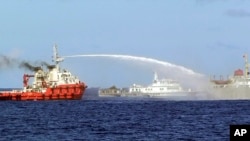 FILE - In this photo released by Vietnam Coast Guard, a Chinese ship (L) shoots a water cannon at a Vietnamese vessel (R) while a Chinese Coast Guard ship (C) sails alongside in the South China Sea, off Vietnam's coast, May 7, 2014. 
